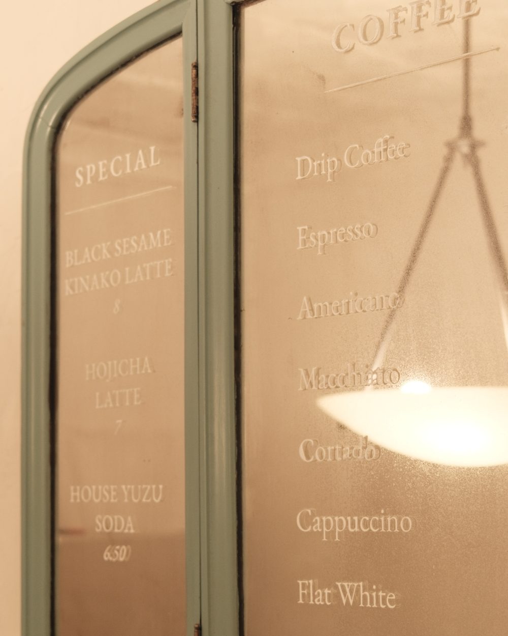 The etched coffee menu on the shop’s mirror