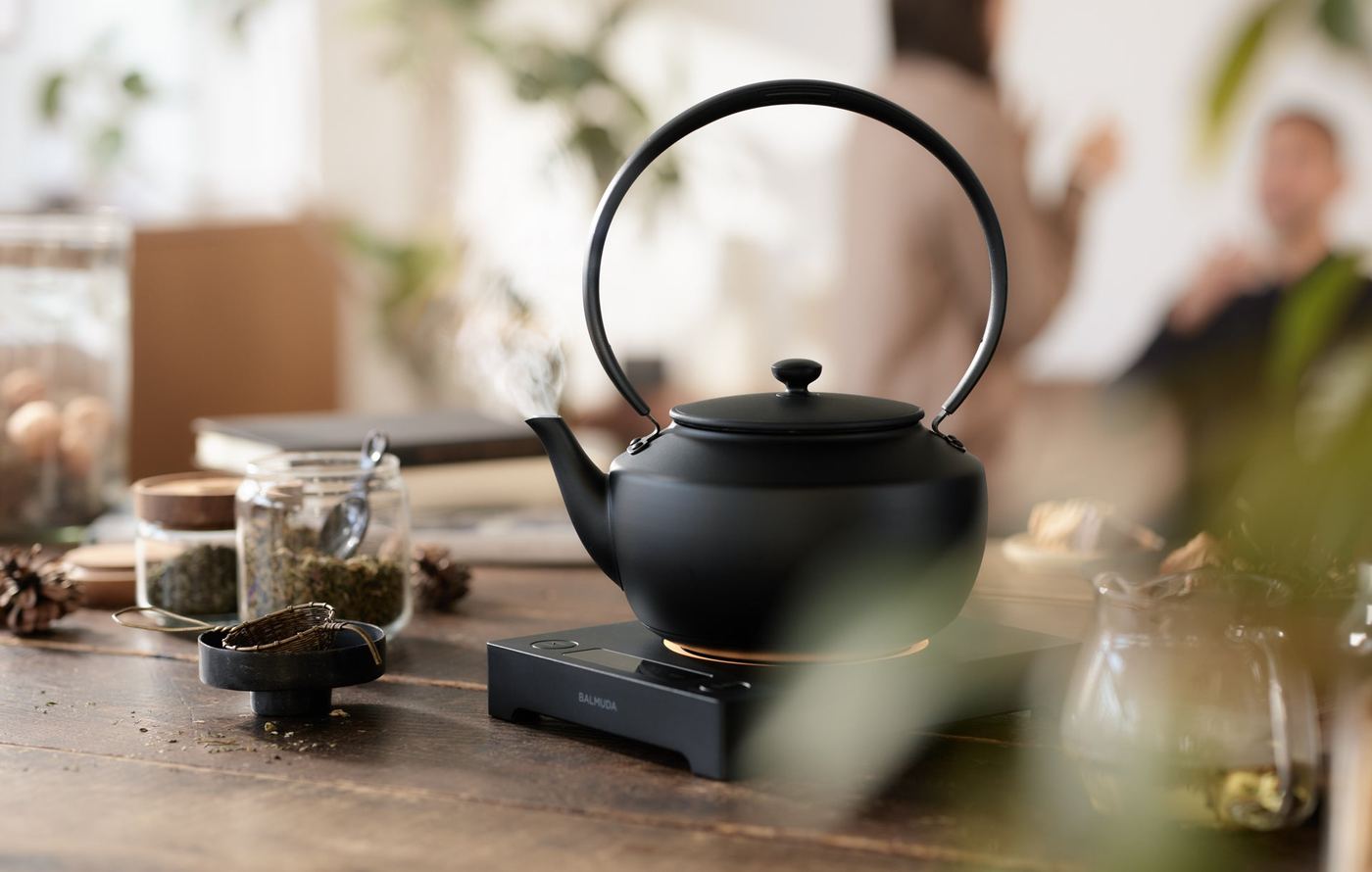 Steam rising from the spout of the BALMUDA MoonKettle on a wooden table