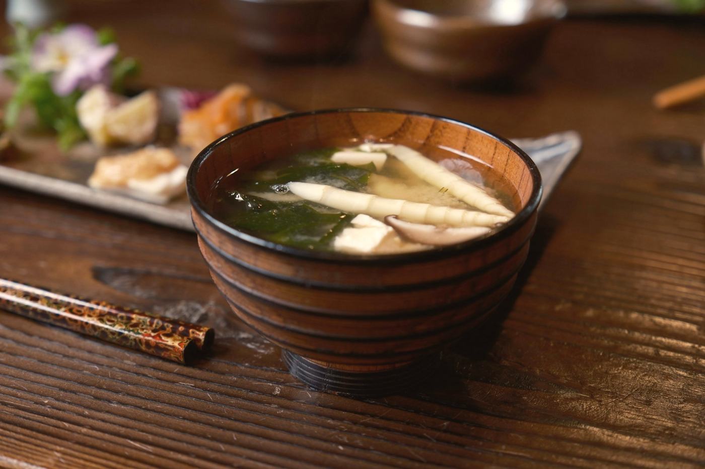 A wooden bowl of miso soup at a breakfast table