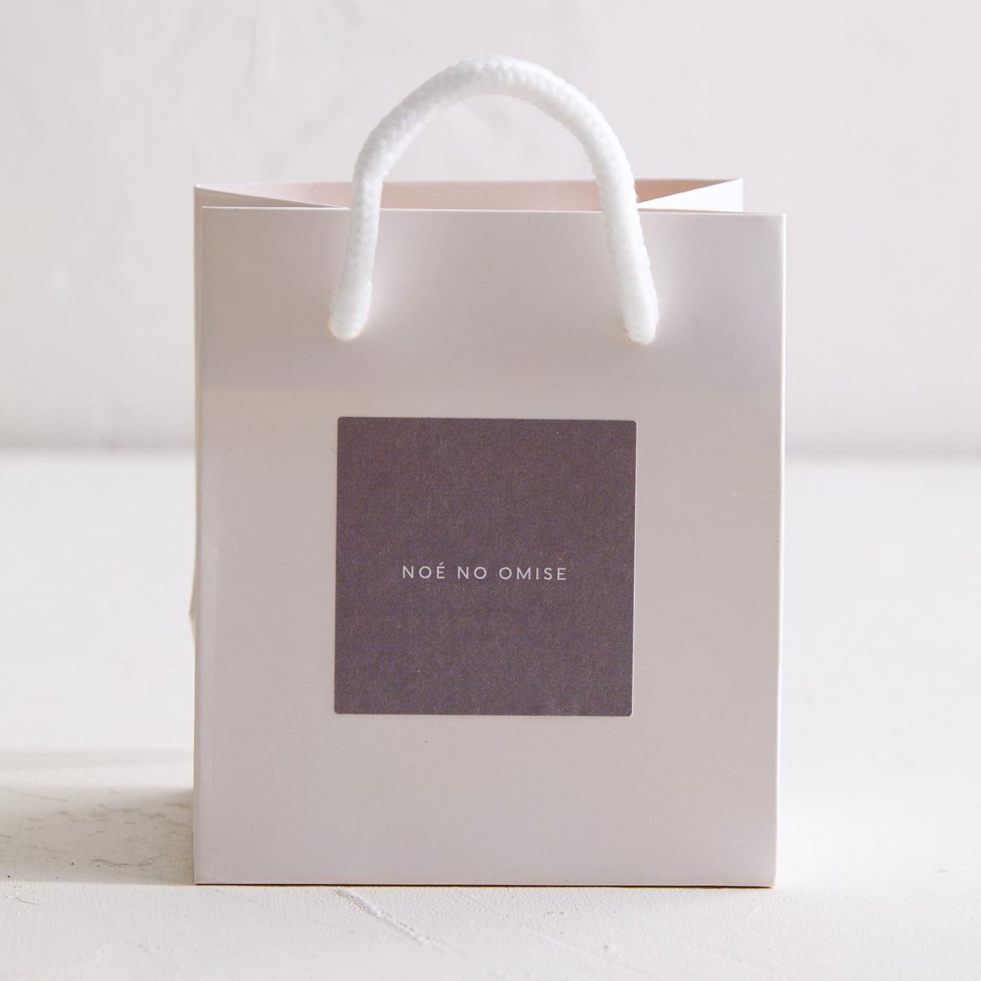 A white NOÉ NO OMISE gift bag