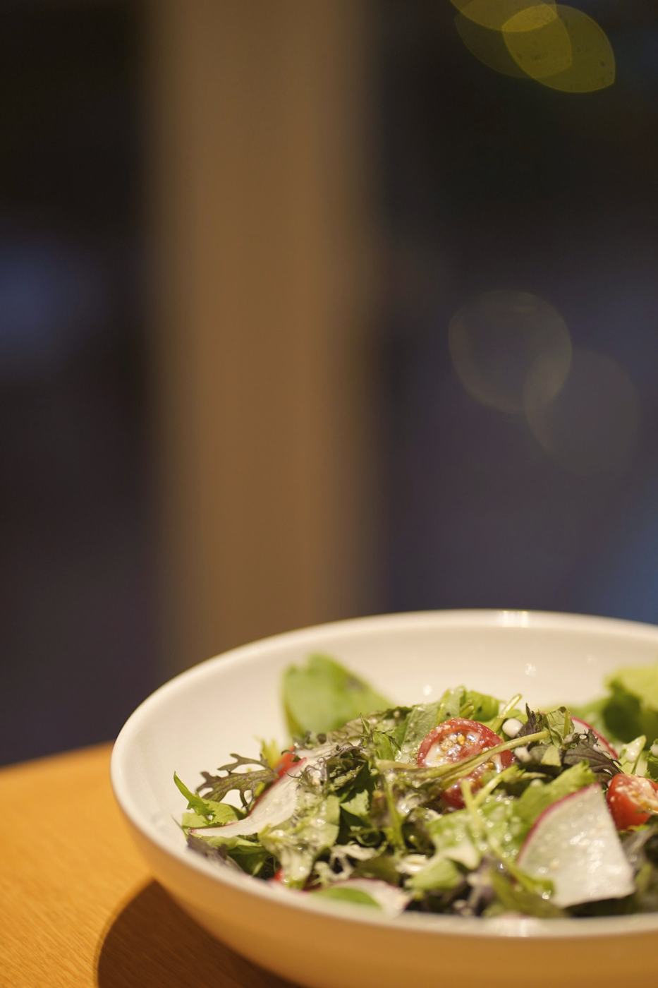 A dressed leafy salad in a white bowl